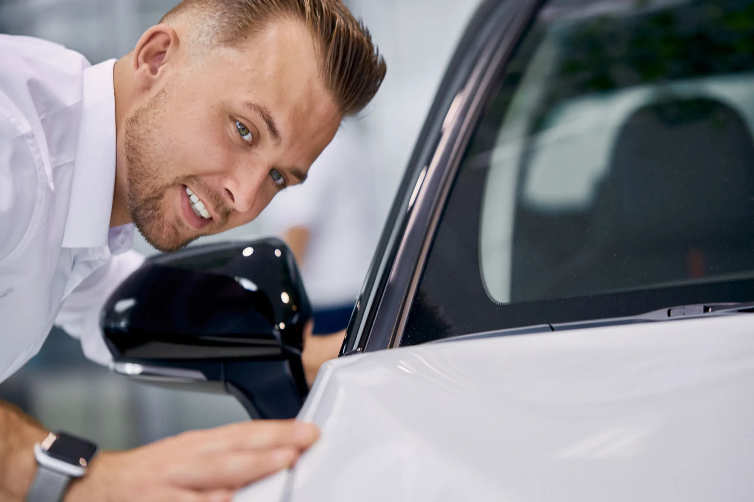 Persoană verificând suprafața și oglinda mașinii înainte de predare